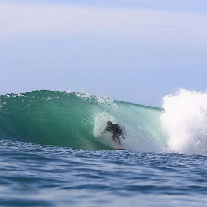 A surfer deep inside the barrel of a clean green wave in Indonesia